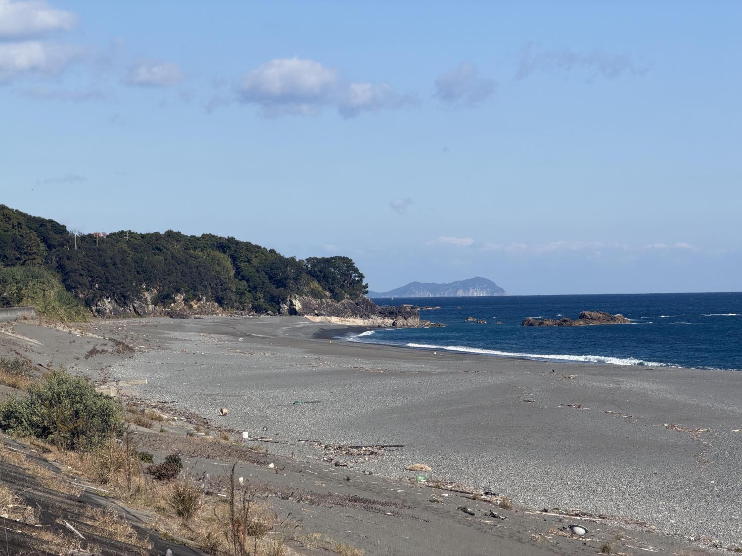 Wide pebble beach meeting the blue Pacific ocean