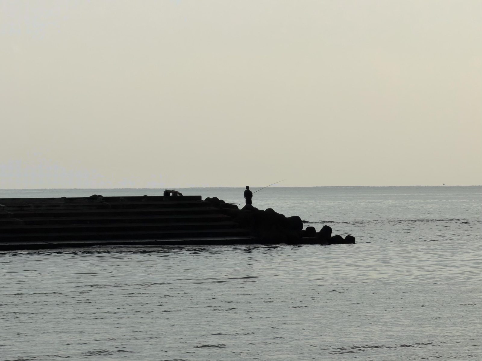 A fisherman working the breakwater
