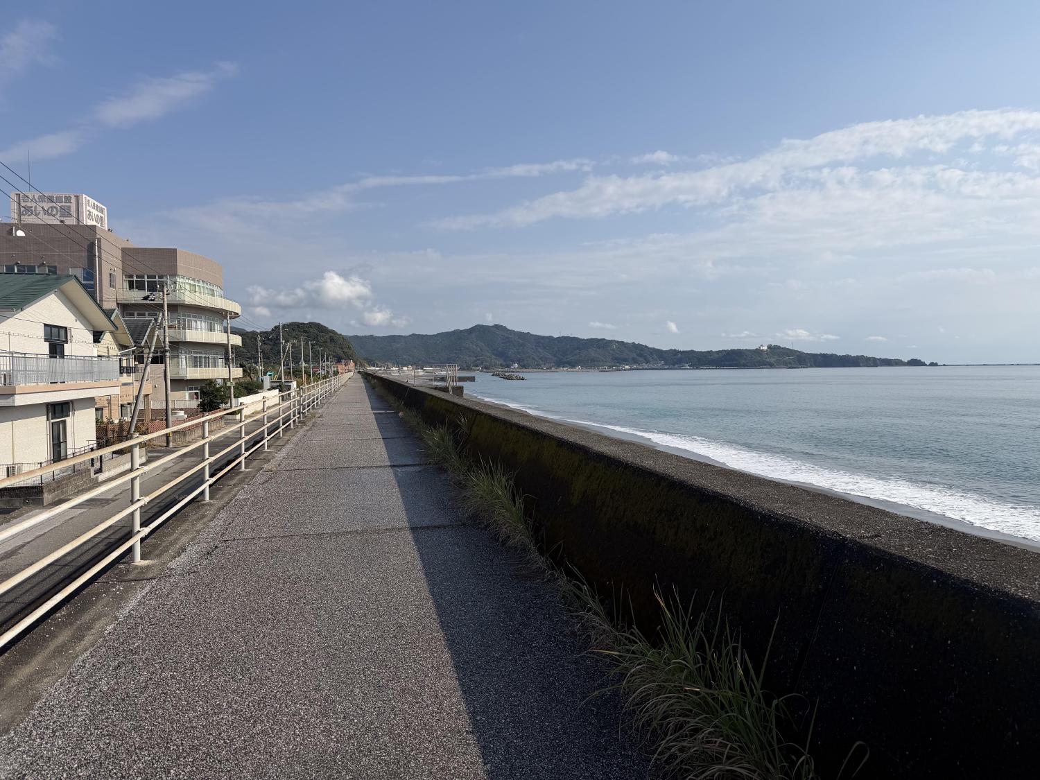 Coastal road beside a seawall and sunlit blue sea